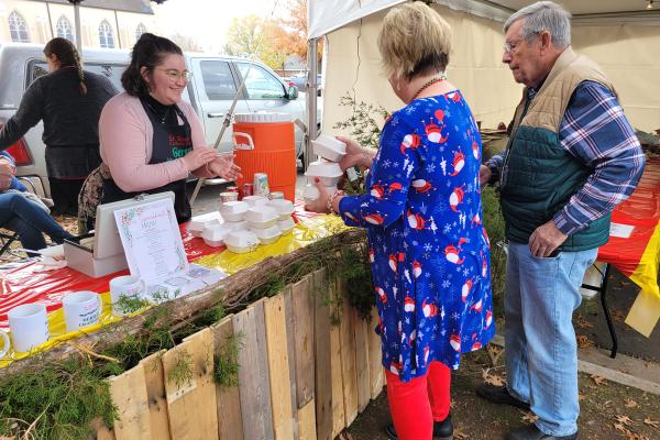 Katie Gramlich (left) and Krystal Summers serve German food and drinks to Judy Brooks and her father, Ed Franz, at Christkindl Market at St. Boniface Church in Fort Smith Dec. 2. Maryanne Meyerriecks