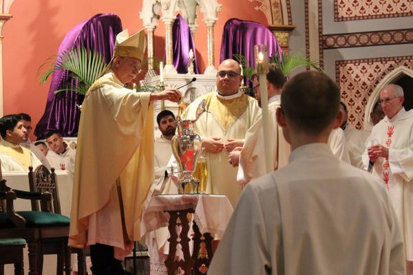 Bishop Anthony B. Taylor (at left), assisted by Father Juan Guido, blesses and pours holy oils during the Chrism Mass March 25 at the Cathedral of St. Andrew in Little Rock. (Katie Zakrzewski)