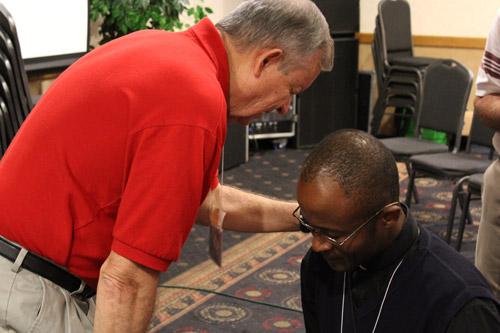 Dr. Dennis Holt of St. Paul Church in Pocahontas prays with Father Elisee Noel at the 2012 Arkansas Catholic Charismatic Conference held in North Little Rock. Photo by Dwain Hebda