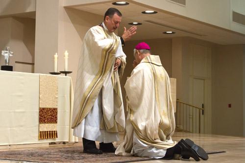 Bishop Taylor kneels before the diocese's newest priest for a blessing. Bob Ocken photo