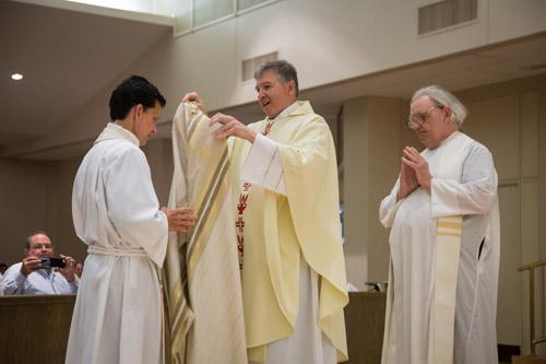 Father John Connell of St. Raphael Church in Springdale invests Rick Hobbs III with the chasuble, indicative of his role as priest. Father Jon McDougal, pastor of St. Boniface Church in Fort Smith, looks on. Bob Ocken photo