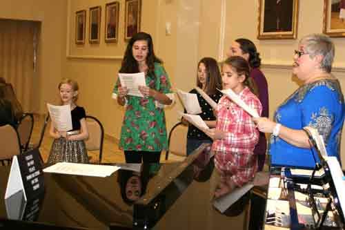 The Cathedral Youth Chorale directed by Ruth Hopper (right) sang Christmas carols at the annual St. Nicholas Party hosted by the Cathedral of St. An-drew on Dec. 14. Lunch was provided, along with St. Nick to take photos with children. (Photo by Aprille Hanson)