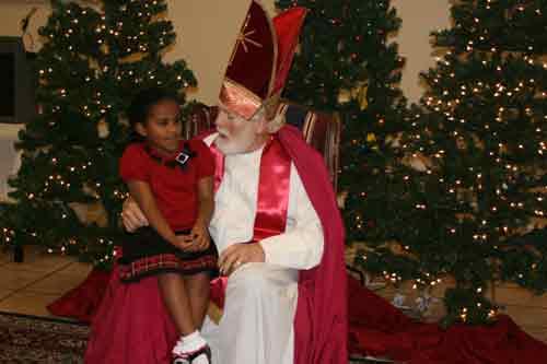 St. Nicholas talks with Sarah Hutchison, 7, about her Christmas wishes for the year at the annual St. Nicholas Party hosted by the Cathedral of St. Andrew on Dec. 14. Jimmy Phillips, a parishioner at St. Andrew, has been playing St. Nick for 14 years. (Photo by Aprille Hanson)