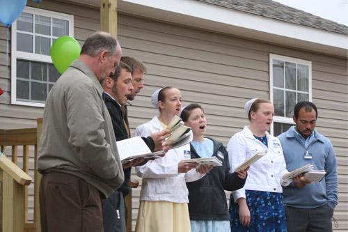 The homes were built by volunteers with Christian Aid Ministries, made up of members of Mennonite and Amish churches. They performed at the ribbon-cutting ceremony March 19. (Aprille Hanson) 