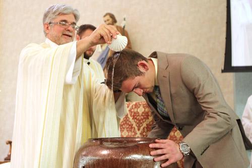 Father John Marconi, pastor of St. Joseph Church in Conway, baptizes Vilonia High School student Andrew Kizer during the Easter vigil Mass April 4. 