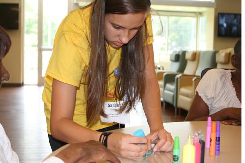 Sarah Schmitz, 16, a member of Sacred Heart Church in Charleston, helps a resident at Carelink Adult Day Care Center with an art project. Youth with the CCSI helped at a variety of work sites during the week-long program, July 12-17. 