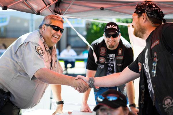 Sgt. Oscar Henson, of the Washington County Sheriff's Department and a St. Raphael parishioner, welcome members of the Northwest Arkansas chapter of Bikers Against Child Abuse who attend Summerfest to create awareness for their cause. (Travis McAfee photo) 
