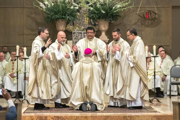 Bishop Anthony B. Taylor kneels before the diocese’s five new priests to receive a blessing May 28 at Christ the King Church in Little Rock. The ordination was one of the largest the diocese has seen in 60 years. ) Bob Ocken / Arkansas Catholic file)