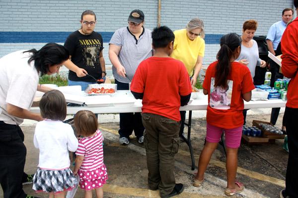 Volunteers from Mercy Hospital Northwest Arkansas (photo at right) serve a meal to children and other residents May 26 at the 8th Street Motel in Rogers where a ministry provides a meal and other essentials. (Alesia Schaefer / Arkansas Catholic file)