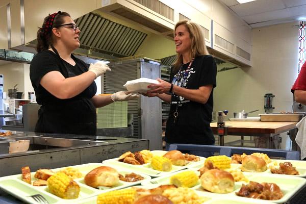 Immaculate Conception School chef Laura Doughty (left) hands a boxed lunch to sixth-grade teacher Alyssa Matthews. The North Little Rock school wanted to give healthier, freshly made food options for students and teachers. (Aprille Hanson photo)