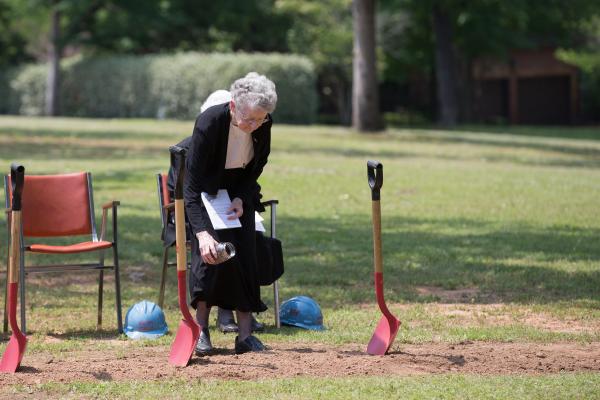 Sister Joella Kidwell, OSB, president of the Federation of St. Gertrude, pours soil from the motherhouse in Ferdinand, Ind., from which four young sisters had journeyed to Arkansas in 1878. 
