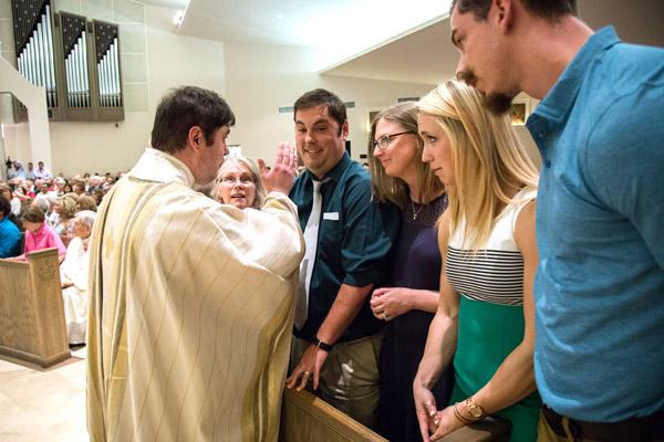 Father Luke Womack blesses his family, including his twin brother Buck, near the end of his priestly ordination Mass. (Travis McAfee photo)