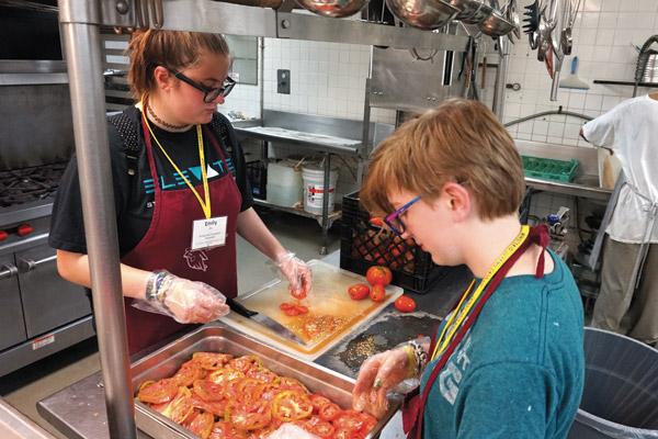 Emily Ellis, 16, (left) and Maggie Williams, 16, both of Immaculate Conception Church in North Little Rock, slice tomatoes at the Little Rock Compassion Center. (Aprille Hanson photo)
