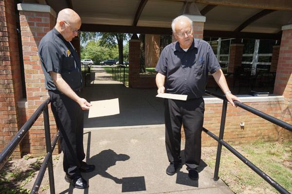 Msgr. Lawrence Frederick “Father Fred” (left) and Brother Richard Sanker try out their pinhole projections of the eclipse on the sidewalk at Catholic High School. 