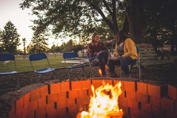As the sun sets, Jessica Fulghum (left) and Mary Engledowl chat and enjoy chili while keeping warm by the fire. (Travis McAfee photo)
