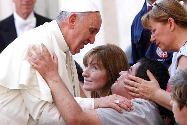 Pope Francis greets a disabled man after celebrating Mass in St. Peter's Square at the Vatican in this June 17, 2013, file photo. The pope has shown special concern for the aged, the sick and those with disabilities. (CNS / Paul Haring)