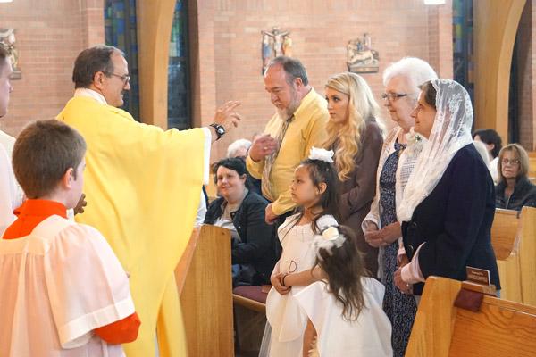 Father Norbert Rappold, pastor of St. Peter the Fisherman Church in Mountain Home, blesses new Catholics as they bring up the gifts during Easter Vigil Mass March 31. They are (from left) Al Moore, Lauren Flowers, Lois Runkle and Patricia Biltoft; Lily Pemberton, 6 (left) and Alli Pemberton, 4. (Aprille Hanson photo)