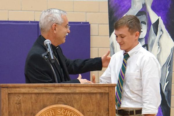Bishop Taylor shakes hands with senior Joseph Jones after signing his letter of intent to discern the priesthood as a diocesan seminarian this fall. (Aprille Hanson photo)