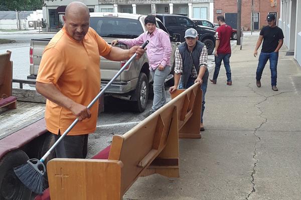 Parishioners of Sts. Peter and Paul Church in Lincoln clean off a pew destined for their officially owned building at 113 Boyer Avenue. Pictured are: Osvaldo Guereca (left), Rogelio Cardenas, Raul Carrillo, Luis Antonio Torres (red shirt) and Jose Manuel Torres. (Maria Elena Ortiz photo)
