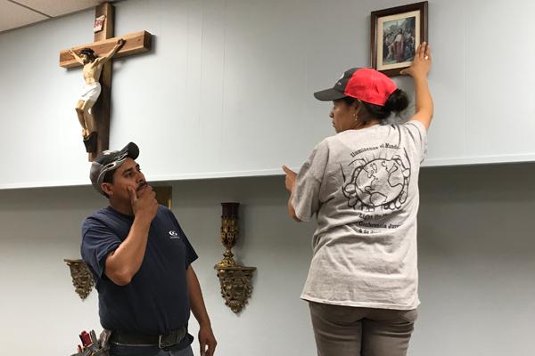 Two days before the dedication of Sts. Peter and Paul Church, parishioners Fernando Cuevas and Maria Elena Ortiz, who helped form what is now the parish, hang pictures in the sanctuary. (Tania Herrera photo)