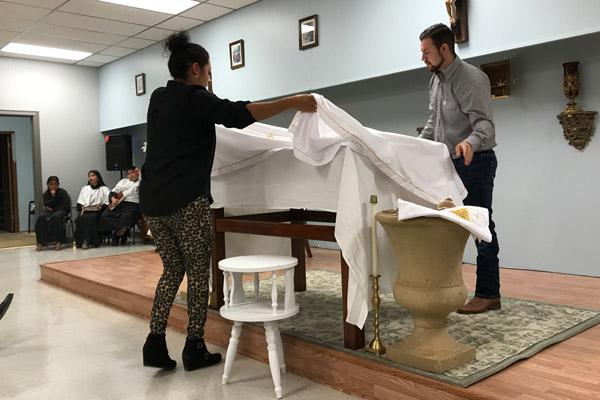 Guadalupe Torres (left) and her son Luis Torres place the altar cloths during the Sts. Peter and Paul Church dedication Mass. (Tania Herrera photo)
