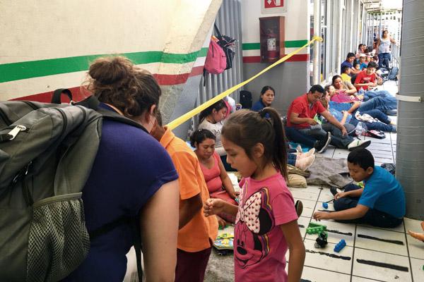 Jennifer Verkamp, director of Catholic Charities Immigration Services - Little Rock (left), speaks to migrant children in Mexico at the border in Nogales on June 2. Verkamp and four others spent a few hours warning parents seeking asylum that they may be separated from their children. (Arkansas Catholic file)