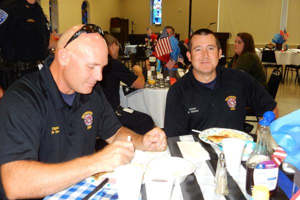 Captain Keith Goss (left) and driver Alan Wilson, both of the Hot Springs Fire Department, eat breakfast prepared by the Knights of Columbus after a Sept. 11 service at St. Mary of the Springs Church in Hot Springs. (James Keary photo)