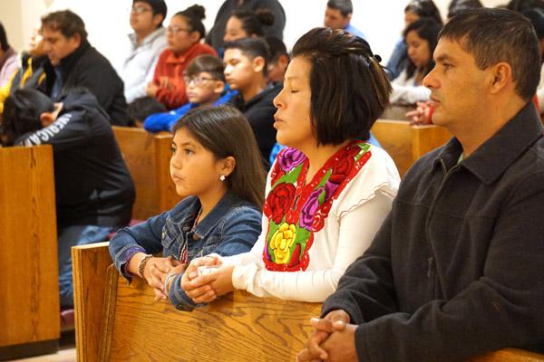 Parishioners Jennifer and Heraclio Rodriguez and their daughter Sosie Claire pray during Mass Nov. 23 to dedicate the new building for St. Luke Church in Warren. (Malea Hargett photo)