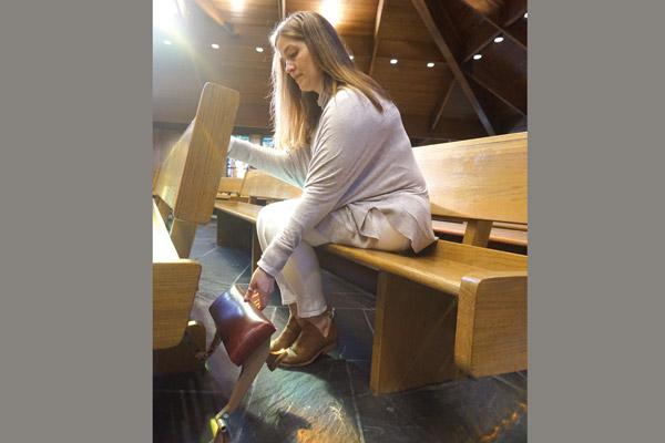 Wendy Floriani puts down the kneeler, typically available in the pew. Catholics and guests are invited to kneel at different parts of the Mass, if able, particularly at the consecration of the Eucharist. (Aprille Hanson)
