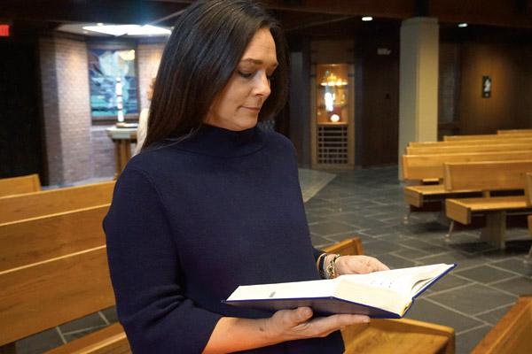 Susie Williams opens a song book in the Our Lady of Holy Souls sanctuary. Because of the dismissal rite, which is a direct mission to “Go forth, the Mass is ended,” faithful are encouraged to stay until the end of Mass. (Aprille Hanson)