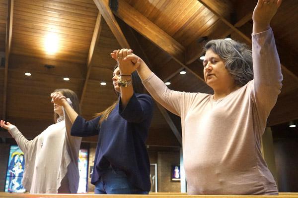 There are various gestures of prayer, including holding hands and raising them at the conclusion of the Our Father prayer during Mass, demonstrated here by Wendy Floriani (left), Susie Williams and Stacey Matchett. There is nothing in Church rubrics that forbid or require congregants to hold hands. (Aprille Hanson)