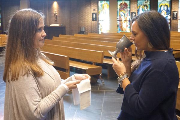 After receiving the body of Christ, a Catholic can choose to receive the blood of Christ, given here by Wendy Floriani to Susie Williams. Following Communion, the faithful should return to their pews for prayer. (Aprille Hanson)