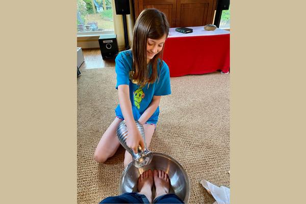 Grace Elizabeth Tucker, 9, smiles as she washes the feet of her mother Jennifer Tucker in their Conway home on Holy Thursday, April 11. Matt and Jennifer Tucker and their four children have been watching Holy Week Masses at home. (Alex Tucker photo) (Not available for sale)