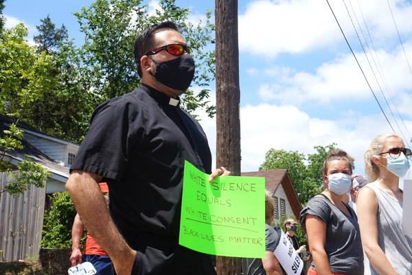 Father Rubén Quinteros, pastor of Immaculate Heart of Mary Church in North Little Rock (Marche), holds a sign at the “Take a Knee - A Rally for Justice” June 6 to speak up against racial injustice. (Aprille Hanson photo)