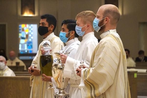 Seminarians Deacon Daniel Velasco (left), Jaime Nieto, Jonathan Semmler and Deacon Joseph Friend present the chrism oil Aug. 10. The oil, mixed with chrism fragrance by the bishop, will be used in the priestly ordinations of Deacons Velasco and Friend Aug. 15. (Aprille Hanson photo)
