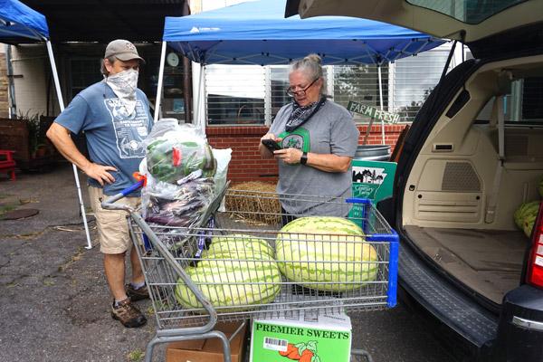 St. Joseph Center of Arkansas executive director Sandy DeCoursey discusses the collected produce for the Farm Stand with volunteer and board member Scott Shellabarger on July 31. The Farm Stand purchases and sells local produce and products. (Aprille Hanson photo)