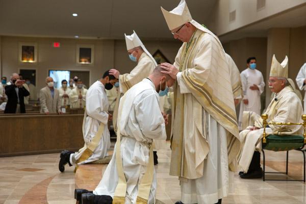 Archbishop J. Peter Sartain lays hands on Father Daniel Velasco (left) and Bishop Francis I. Malone (standing right) lays hands on Father Joseph Friend during their ordination Mass at Christ the King Church in Little Rock Aug. 15, the solemnity of the Assumption. Archbishop Sartain, who served in Arkansas from 2000-2006, is now retired in Arkansas. Bishop Malone, former Christ the King pastor, serves in Shreveport, La. (Bob Ocken photo)