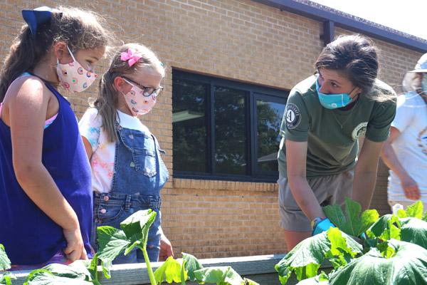 Rising fourth-grade students Clara Hum (left) and Blair Bramlett, both 9, have been volunteering this summer in the garden at Immaculate Conception School in North Little Rock and learning lessons from Americorps volunteer Carey McKay. (Aprille Hanson photo)