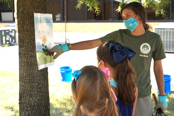 AmeriCorps volunteer Carey McKay points out the parts of a plant to rising fourth-grade students Blair Bramlett (left) and Clara Hum. McKay and three other volunteers will be at the school teaching lessons to students through September.  (Aprille Hanson photo)
