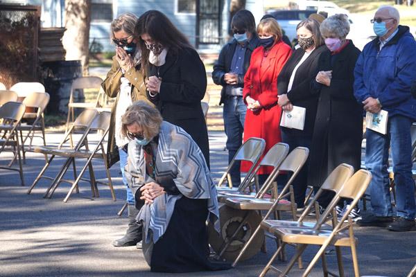Terry Crow (left), Kristin McConnell and her mother Taffy Council pray and kneel during the All Souls’ Day Mass at Calvary Cemetery in Little Rock Nov. 2. Council’s husband, Dr. Tony Council died Feb. 14, 2020, and is buried at Calvary. His name was read during Mass in the list of the deceased from 2020. (Aprille Hanson photo) 