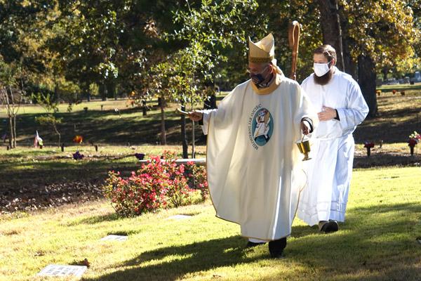 Bishop Taylor blesses graves in Priests’ Circle for All Souls’ Day Nov. 2, with seminarian James Freeman assisting. (Aprille Hanson photo) 