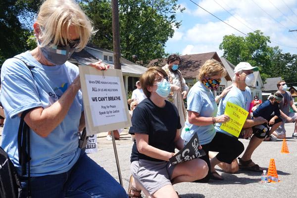 Pax Christi Little Rock members Mary Hunt (left), Marian Paquette, president Sherry Simon and George Simon take a knee for prayer and a stance against police brutality at a June 6 rally in Little Rock. (Aprille Hanson photo, Arkansas Catholic file)