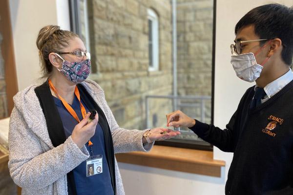 Subiaco Academy senior Andrew Bui takes a jelly bean from school nurse Barbara Wilhelm Feb. 3 during morning check-in. Wilhelm tests students' sense of taste and smell using candy and essential oils to help detect COVID-19 symptoms. (Blake Zimmer, Subiaco Academy)