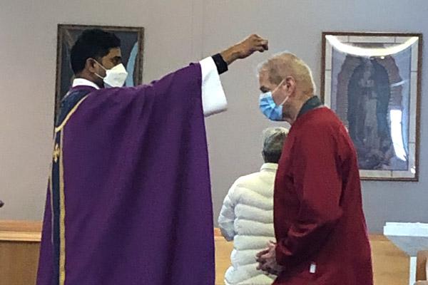 Father Chandra Kodavatikanti, associate pastor at St. Joseph Church in Fayetteville, sprinkles ashes on the head of Deacon Norm DeBriyn during the noon Mass on Ash Wednesday, Feb. 17. The winter storm affected Ash Wednesday Masses. (Father Jason Tyler photo)