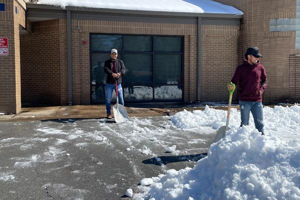 Marcos Diaz (left) and Gerardo Leon survey a small mountain of snow they helped create in the parking lot of St. Theresa Church in Little Rock Feb. 20. They are part of a group of volunteers who descended upon the church with a variety of shovels, scrapers and a Bobcat front-end loader to clear about a foot of snow from church and school sidewalks and parking lots. (Father Nelson Rubio photo)