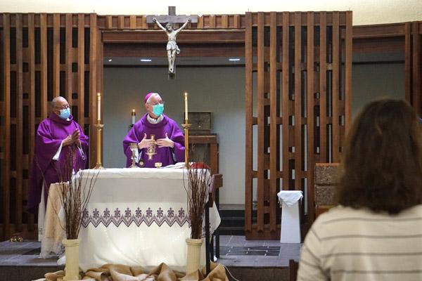 Bishop Anthony B. Taylor opens Mass Feb. 23 at the CHI St. Vincent Infirmary chapel in Little Rock for all the souls who have died from COVID-19 and health care workers. Chaplain Father Warren Harvey concelebrated, as nurse Amanda Matkovic looks on. (Aprille Hanson photo)