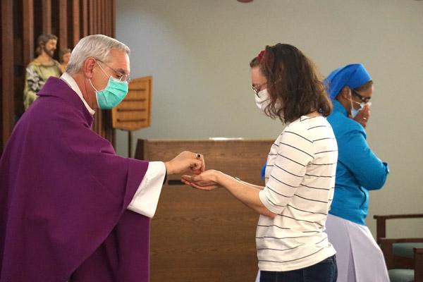 Amanda Matkovic, a nurse in medical oncology and pre-postulant for the Daughters of Charity, receives Communion from Bishop Anthony B. Taylor Feb. 23 during Mass at CHI St. Vincent Infirmary’s chapel. (Aprille Hanson photo)
