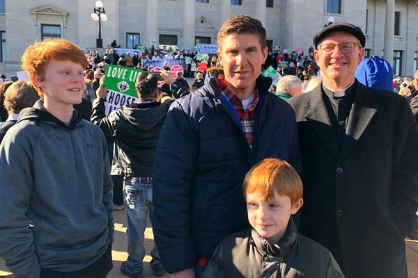 Father James West, then pastor at St. Edward Church in Texarkana, poses with parishioners Donny Thompson, Jacob Thompson (left) and Owen Thompson at the January 2020 March for Life in Little Rock. Father West was found dead from a heart attack in his rectory March 8, 2020. (Courtesy Thompson family)