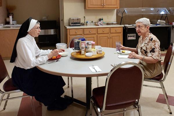Sisters Sarto Gaffney (left) and Jolitta Konecny, RSM, chat at dinner March 3 at McAuley Convent in Barling. (Maryanne Meyerriecks photo)
