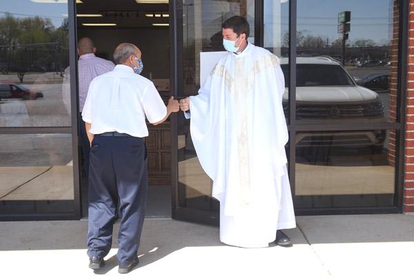 Father Tony Robbins fist-bumps Jose Gomez as he enters St. Oscar Romero Catholic Community in Greenbrier for the Spanish Mass on Easter, April 4. The community held its first Masses in the space since the pandemic began in March 2020. (Aprille Hanson Spivey photo)